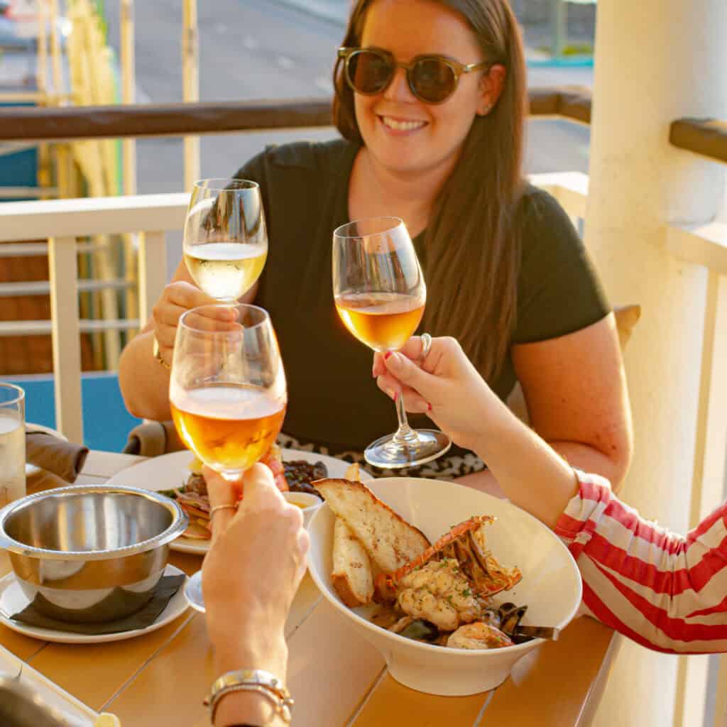 A group of friends enjoying seafood and toasting with glasses of wine at Guy Harvey’s Boathouse Grill